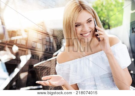 Chit chatt. Wonderful pleasant appealing  woman laughing while looking aside and taking on the phone