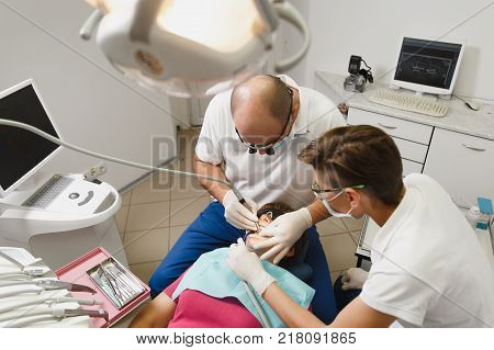 Process Of Preparing And Installing Dental Ceramic Crown. Male Professional Dentist And Female Assis