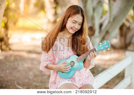 Asian Lady With Hat Play Ukulele Bossanova Music In Summer Time.young Cute Woman Playing Music Outdo