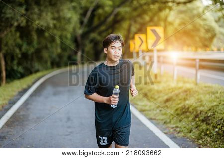 Active healthy runner jogging outdoor. Dinking water.