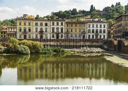 Scenic view of the Lungarno at historic center of Florence, Italy. Facades of old medieval houses on waterfront of the Arno River. Florence is a popular tourist destination of Europe.