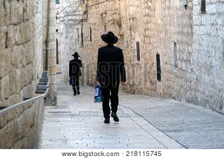 Two unrecognized religious jewish men walking down the street in Old City of Jerusalem.