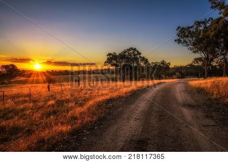 Scenic countryside landscape with rural dirt road at sunset in Australia