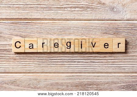 Caregiver word written on wood block. Caregiver text on table concept.