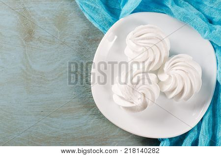 Fresh delicious white meringue cookies served on white plate.