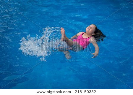 Young Girl Floating in Pool Making Splash with Her Legs