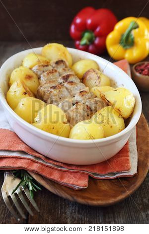 Braised meat paupiettes with potatoes in ceramic bakeware and two bell peppers rustic style