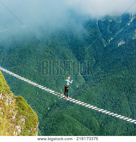 Woman crossing the abyss on the rope bridge.