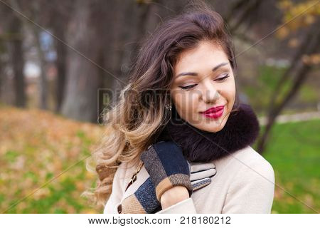 Young brunette woman in gray woolen coat on background autumn park