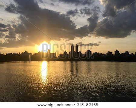 Silhouette Buildings in Manhattan and cloudy sunset sky over lake at Jacqueline Kennedy Onassis Reservoir