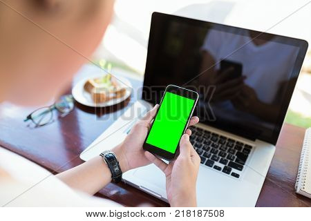 girl using smart phone in cafe. hand holding smart phone green screen. black color smart phone vintage tone. hand holding using mobile phone in coffee shop