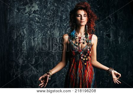 Beautiful bright woman with curly foxy hair wears a dress and beads in boho style. Ethnic style in clothes.