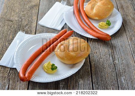 German street food: Hot Debreziner sausages  with spicy mustard and a fresh roll on a paper plate