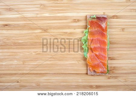 Low caloric open sandwich with red fish on wooden background.