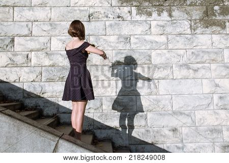 A girl with a bouquet dances with her shadow toned