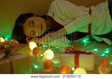 Pretty Vietnamese young woman sleeping after Christmas celebtration