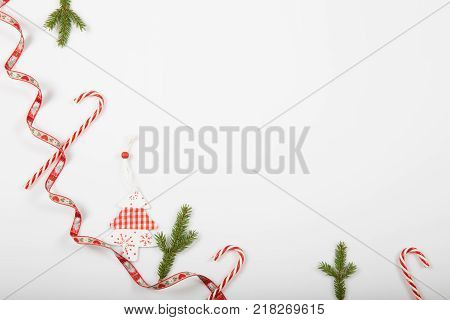Christmas holiday composition. Festive creative red pattern, xmas handmade decor holiday with ribbon, candy canes, gift, christmas tree and decorations on white background. Flat lay, top view