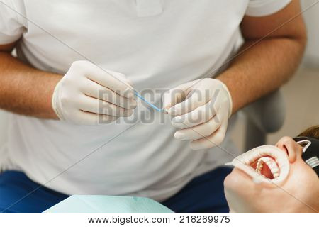 Process Of Preparing And Installing Dental Ceramic Crown. Male Professional Dentist And Female Assis