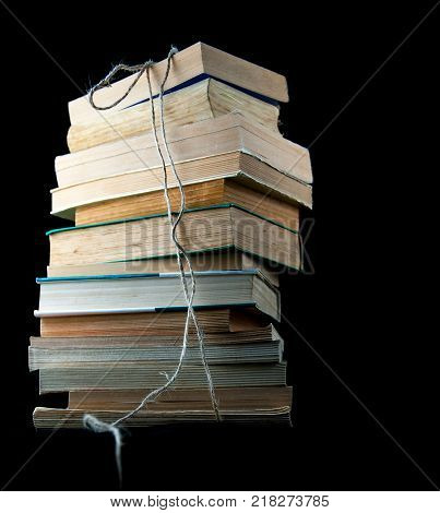 Old books isolated on black background, with hemp rope.