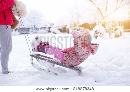 a small child on a sled. girl rolls on snowdrifts in winter sun shines