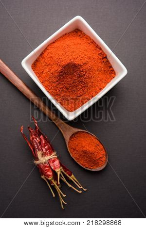 Red Chilly Powder in a bowl with dried red chillies over colourful background or pile of red chilli powder over plain background