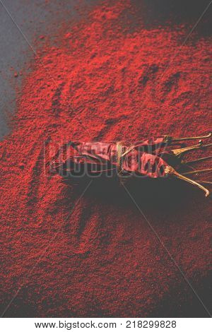 Red Chilly Powder in a bowl with dried red chillies over colourful background or pile of red chilli powder over plain background