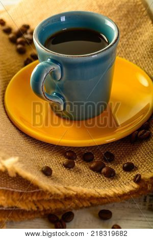 coffee cup with coffee beans liyng in the background