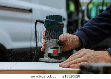 workers using electric routering to cut down stripes on the wood.