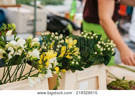 A small business for selling flowers. The seller does the work in the background. Street shop. There are different kinds of flowers on the counter