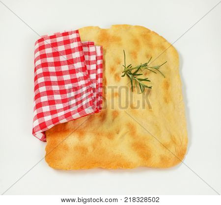 piece of traditional Tuscan flatbread (Ghiottina Toscana) and checkered place mat on white background