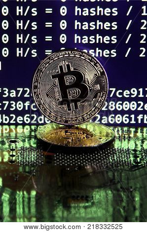 The digital process of cryptocurrency mining by using the GPUs. Bitcoins and video card on a working display and mining screen