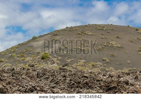 Landscape of Timanfaya National Park in Lanzarote, Canary Islands, Spain. Red and black volcanic mountains.