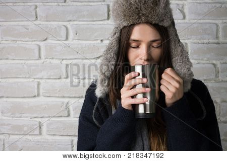 Girl in a hat drinking from a mug