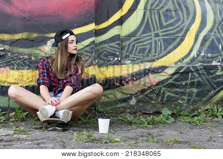 Teen Girl Sitting on Skateboard with Coffee