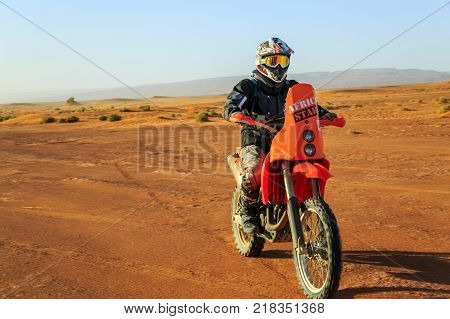Ait Saoun Morocco - February 22 2016: Unidentified man in helmet riding bike in Ait Saoun desert of Morocco.