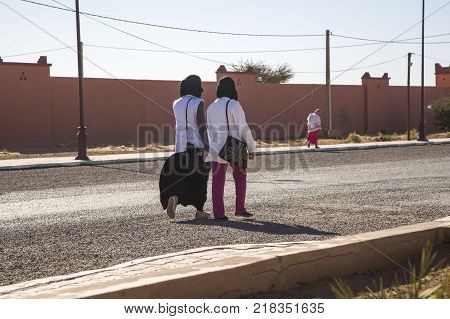 Ait Saoun Morocco - February 23 2016: Two unidentified women in conversation and talking while walking on streets of Ait Saoun village in Morocco.