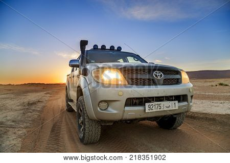 Ait Saoun Morocco - February 23 2016: Toyota Hilux in Ait Saoun desert in Morocco with sunset horizon background.