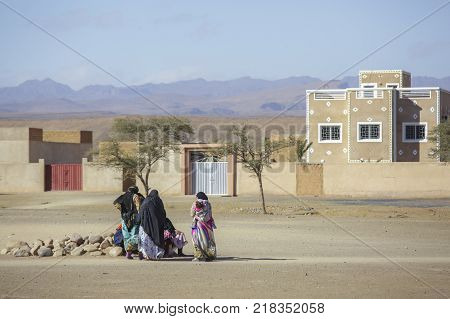 Tinghir Morocco - February 27 2016: Women sitting outside sand house on rocks talking to each other in Tinghur city of southern Morocco. Tinghir city is at the center of one of the most attractive oases in southern Morocco.