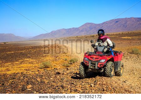 Ait Saoun Morocco - February 22 2016: Man riding atv quad bike on sand in desert on a sunny day in Ait Saoun desert in Morocco.