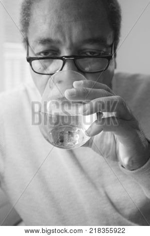 African american male senior taking his high blood pressure medication at home.