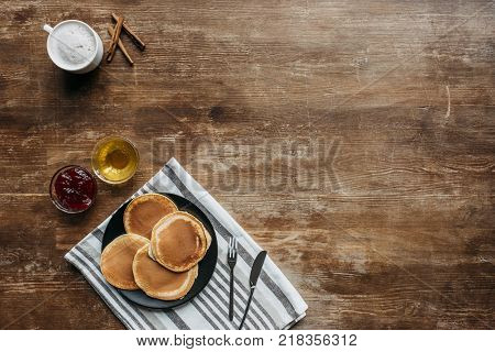 top view of pancakes on striped napking and coffee cup on wooden table