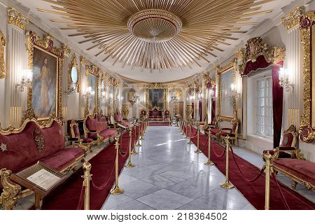 Cairo, Egypt - December 2, 2017: Throne Hall at Manial Palace of Prince Mohammed Ali Tewfik with ornate ceiling inspired by the old flag of the ottoman empire gold plated armchairs and red carpets