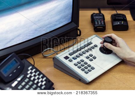 Workplace. CCTV. Female hand on the control panel. Walkie-talkie next to the monitor.