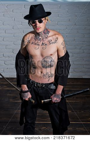 Warrior In Black Hat And Open Clothes Showing Tattooed Torso. Samurai Buddhist Concept. Honor And Di