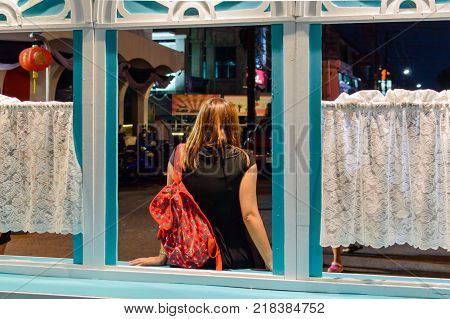 Back view portrait of a single relaxed girl outside through a window.