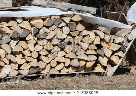 Cut, split and stacked wood and covered to keep it dry, ready for sale for firewood