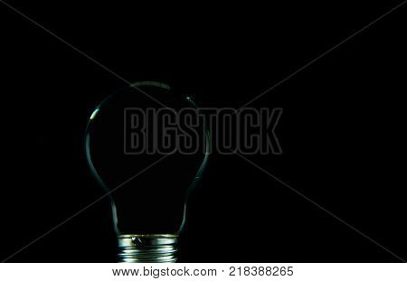 Empty light bulb silhouette isolated on black background.