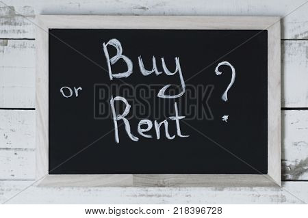 Buy or rent concept. Handwritten text on blackbord. Choosing between renting (leasing) and buying property