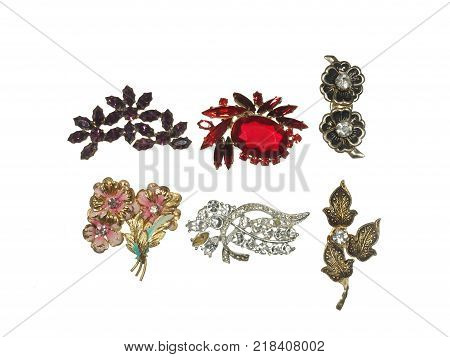 Old brooches with flowers of metal and colorful glass isolated on white background.