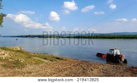 Farmer in the red tractor is washing potatoes in Danube river